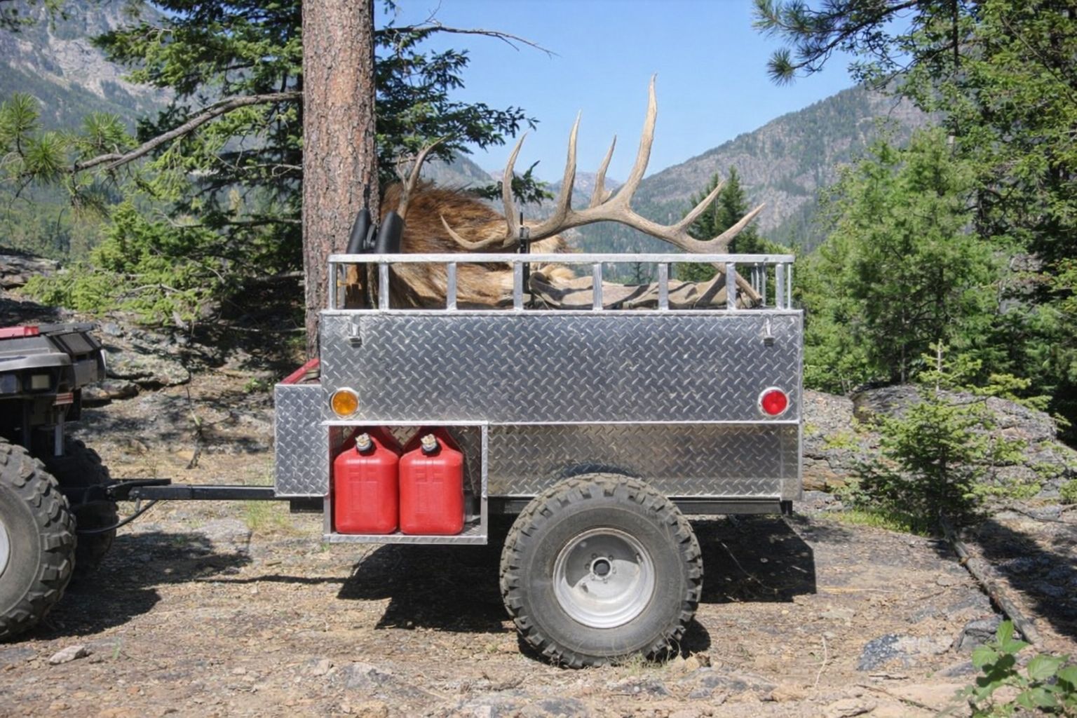 En fyrhjuling med släpvagn lastad för jakt och transport i skogsmiljö.